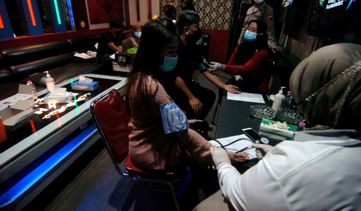 Ilustrasi: petugas memeriksa kesehatan pekerja tempat hiburan sebelum menyuntikkan vaksin COVID-19 di salah satu tempat karaoke