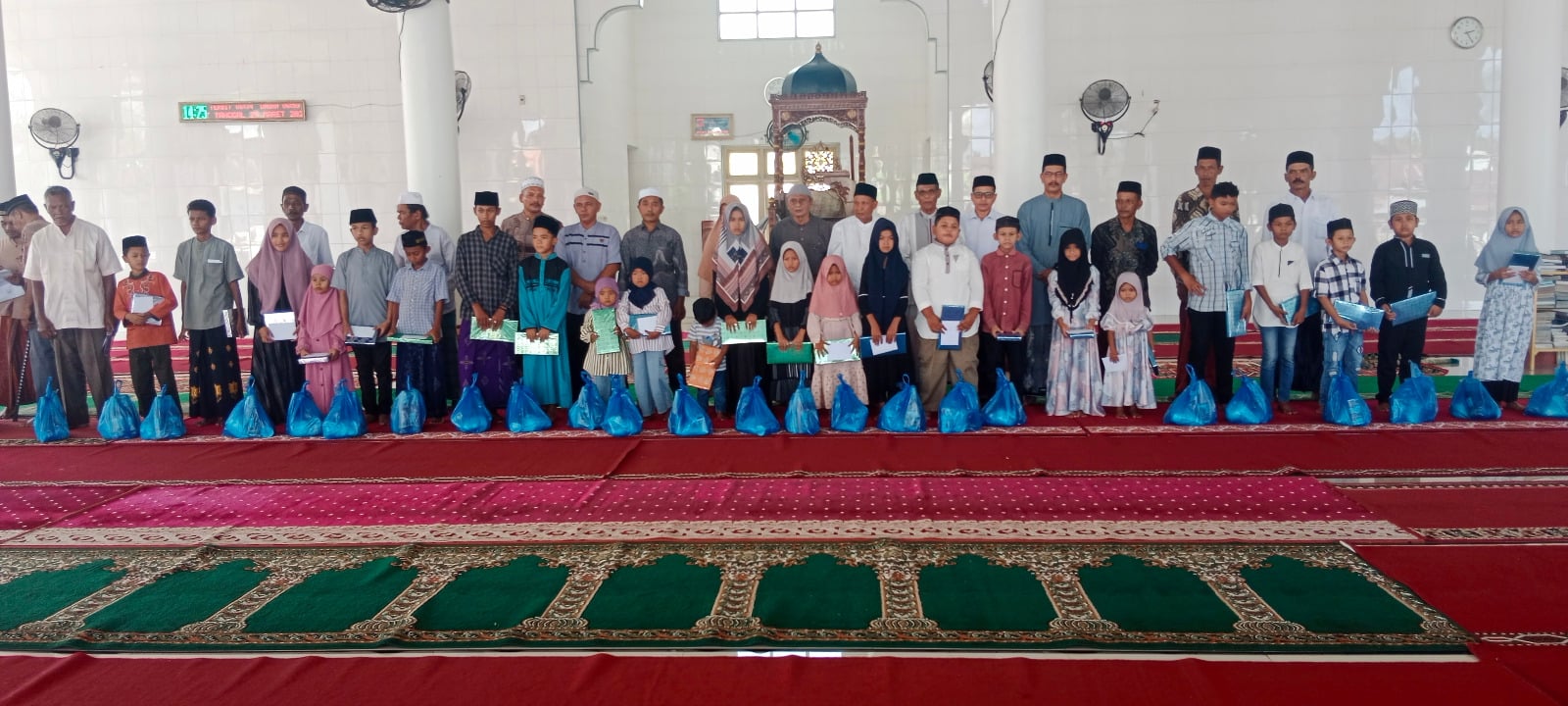  Aksi penyerahan bantuan uang tunai untuk baju baru anak yatim di Masjid Taqwa Lampoih Saka, Kecamatan Peukan Baro, Kabupaten Pidie, Aceh. 