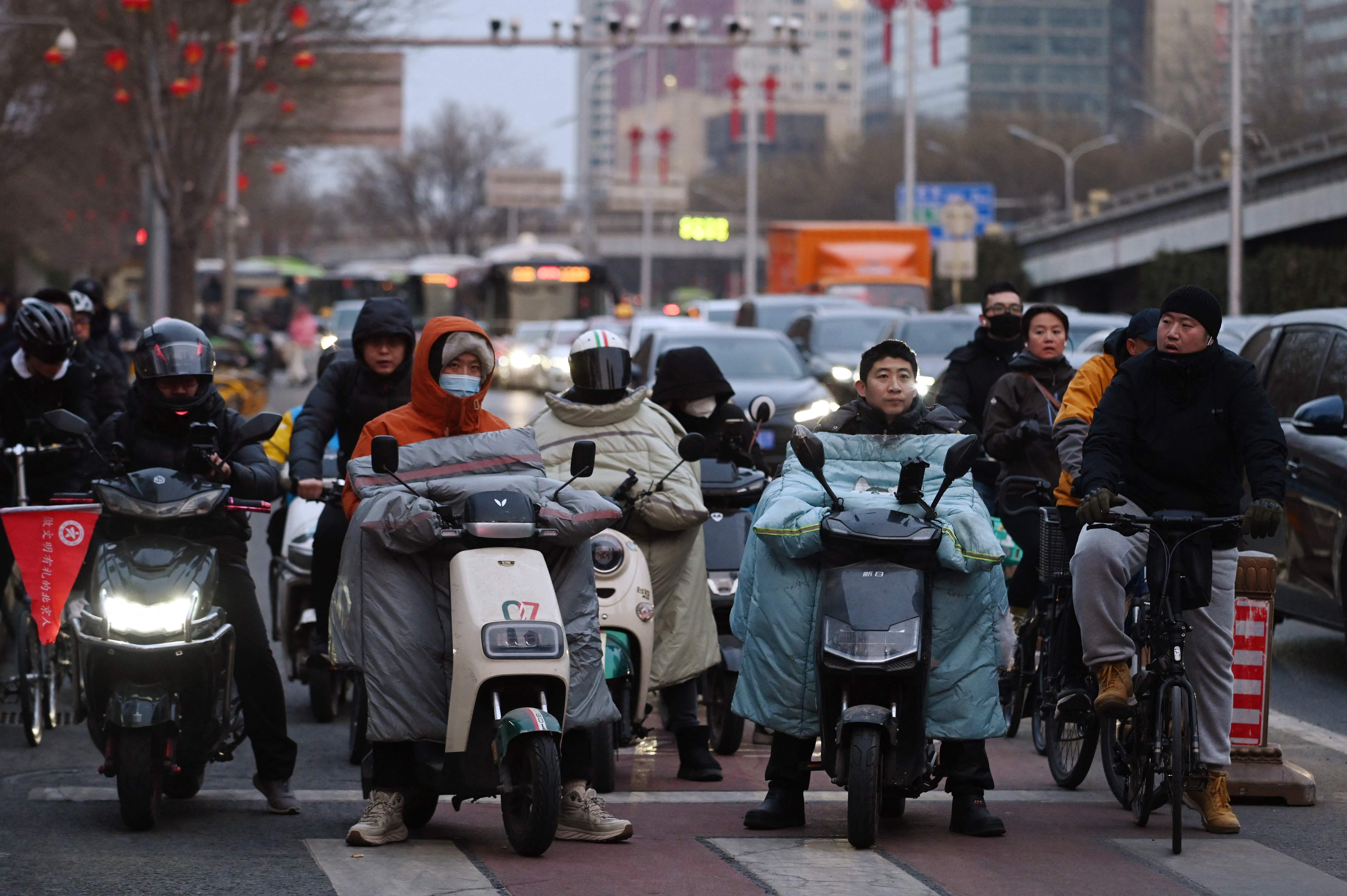 Orang-orang menunggu untuk menyeberang jalan di kawasan pusat bisnis di Beijing pada 28 Februari 2024.