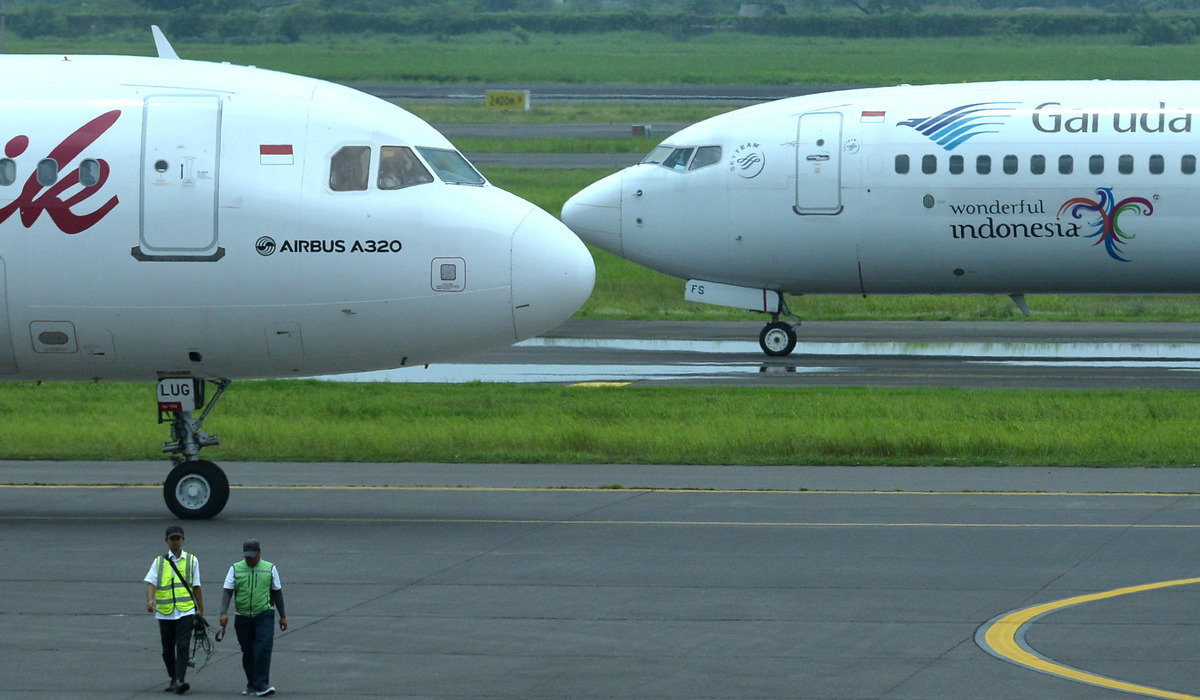Petugas berjalan di depan pesawat Garuda Indonesia dan Batik Air.