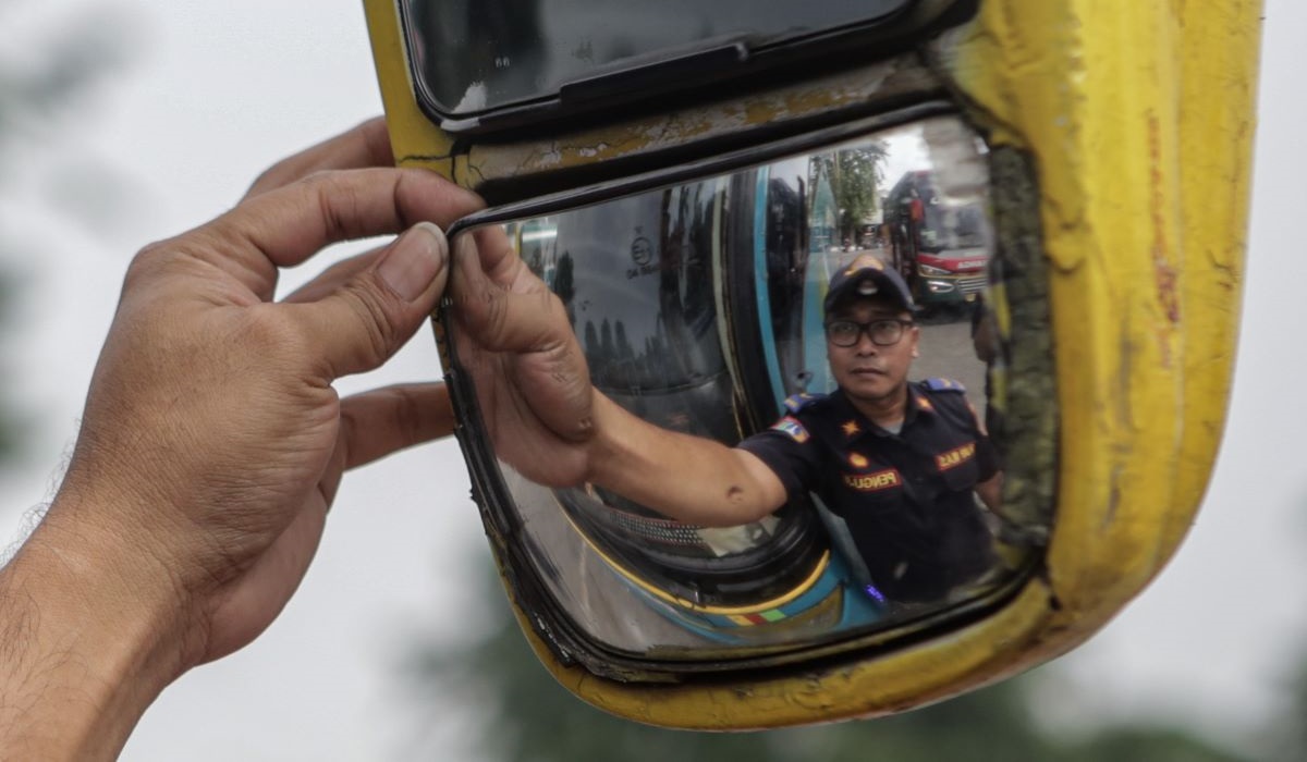 Petugas memeriksa kondisi kaca spion bus. 