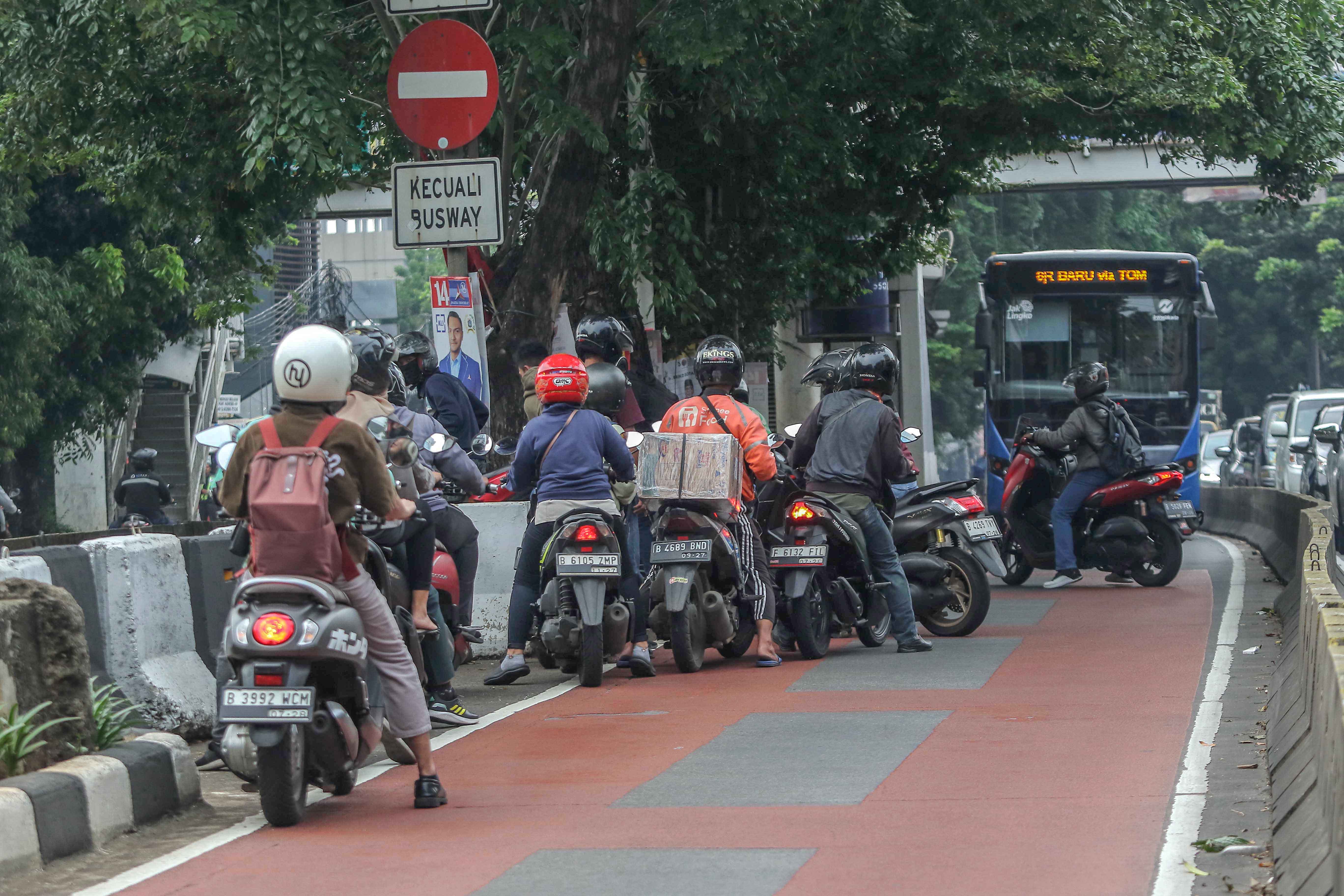 Para pengendara motor memutar balik saat menerobos jalur busway 