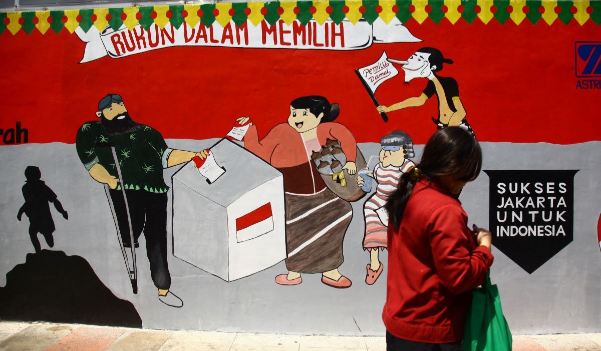 Warga berjalan di depan mural bertema Pemilu 