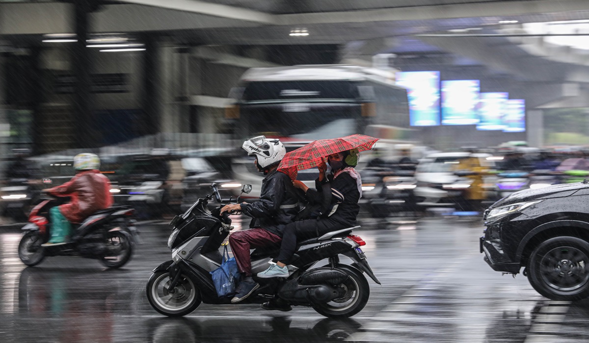 Pekerja memakai payung untuk menghiindari guyuran hujan saat dibonceng motor melintas di kawasan Blom M, Jakarta Selatan.