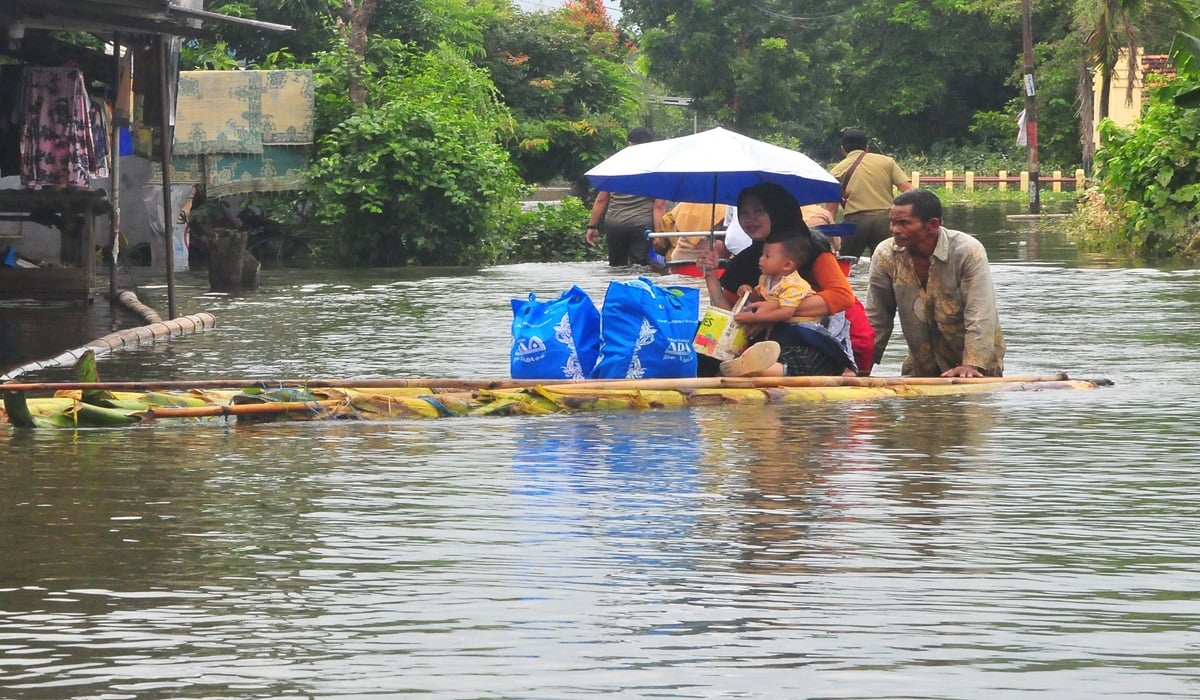 Warga menaiki rakit batang pohon pisang saat melintasi jalan yang terendam banjir di Setrokalangan, Kaliwungu, Kudus, Jawa Tengah.