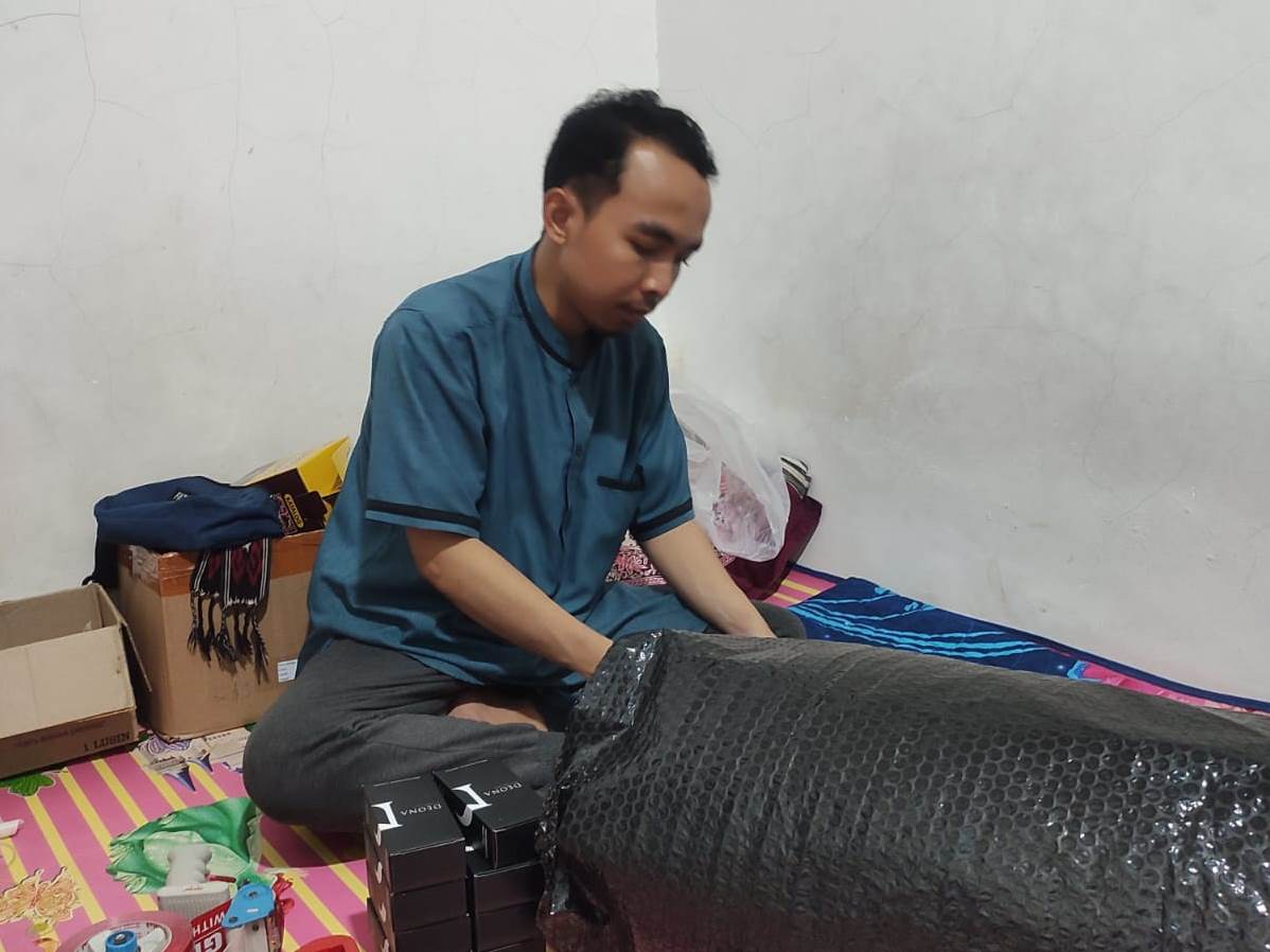 Alfi mengemas pesanan produk yang dijual sebagai pengecer