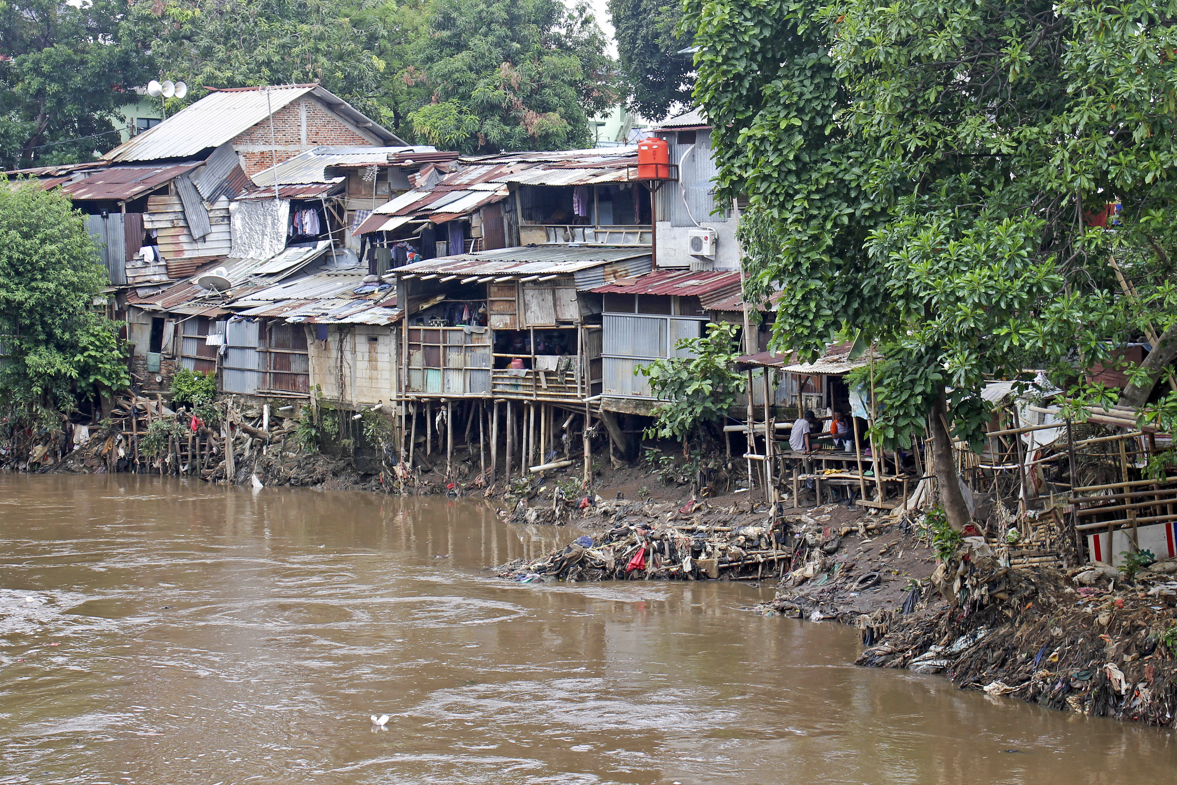 Sejumlah warga duduk di rumahnya di bantaran kali Ciliwung kawasan Manggarai, Jakarta, Senin (13/11/2023). 