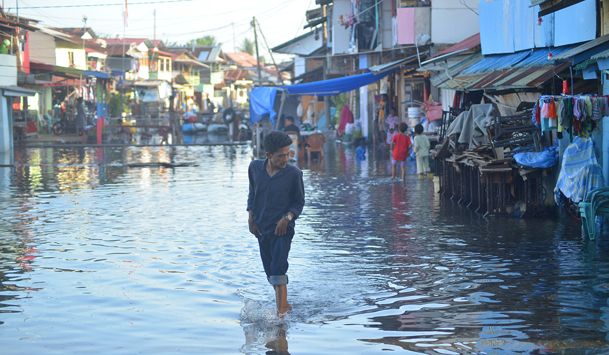 Warga melewati banjir rob yang menggenangi kawasan perkampungan nelayan di Purus Atas, Kota Padang, Sumatera Barat, Rabu (18/5/2022).