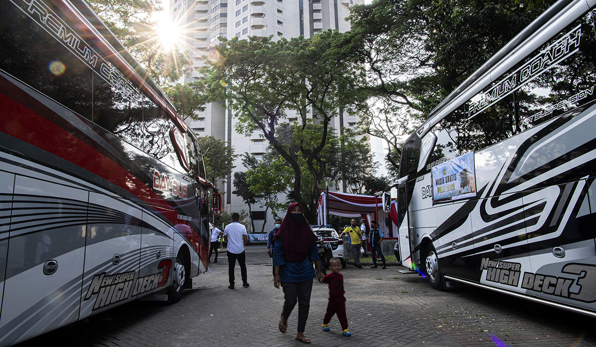 Pemudik berjalan di dekat bus dalam Mudik Gratis Polri 2022 di kompleks Gelora Bung Karno, Jakarta, Senin (25/4/2022).