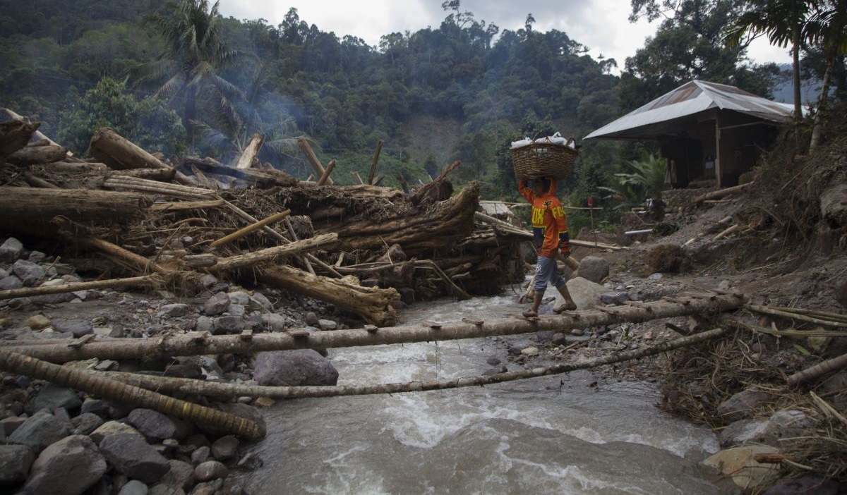 Warga memanggul karung berisi bantuan untuk korban banjir bandang dan longsor di Langgai, Gantiang Mudiak Utara Surantiah, Pesisir Selatan.