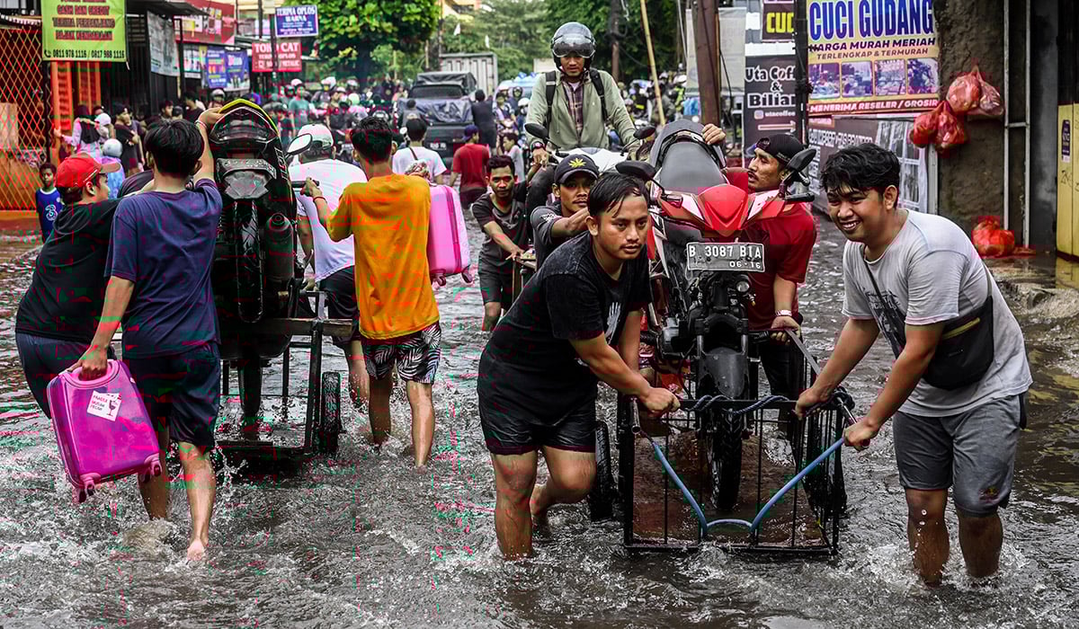 Sejumlah warga membawa motor di atas gerobak untuk melintasi banjir di kawasan Joglo, Jakarta, Jumat (22/3).