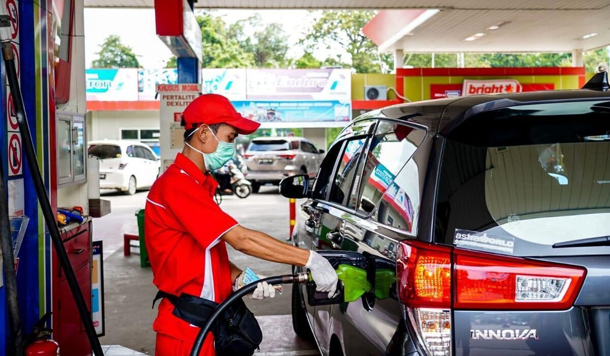 Petugas di SPBU sedang mengisi BBM kendaraan konsumen.