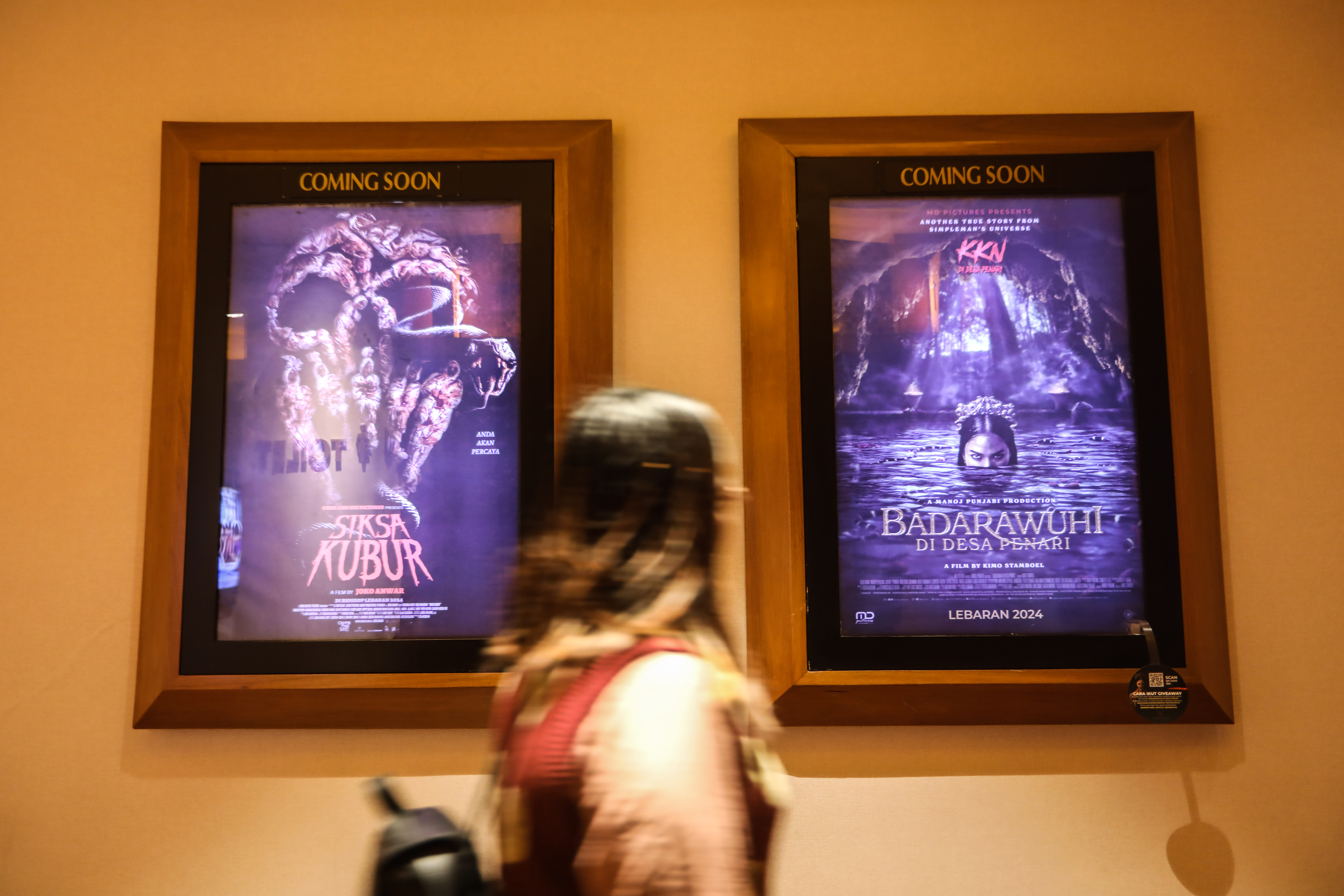 Pengunjung melintas di depan poster film horor Siksa Kubur dan Badarawuhi di Desa Penari 