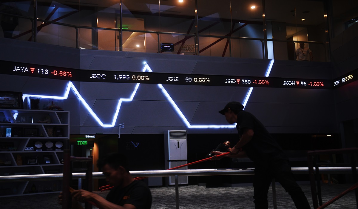 Pekerja melintasi layar digital pergerakan saham di Bursa Efek Indonesia, Jakarta.