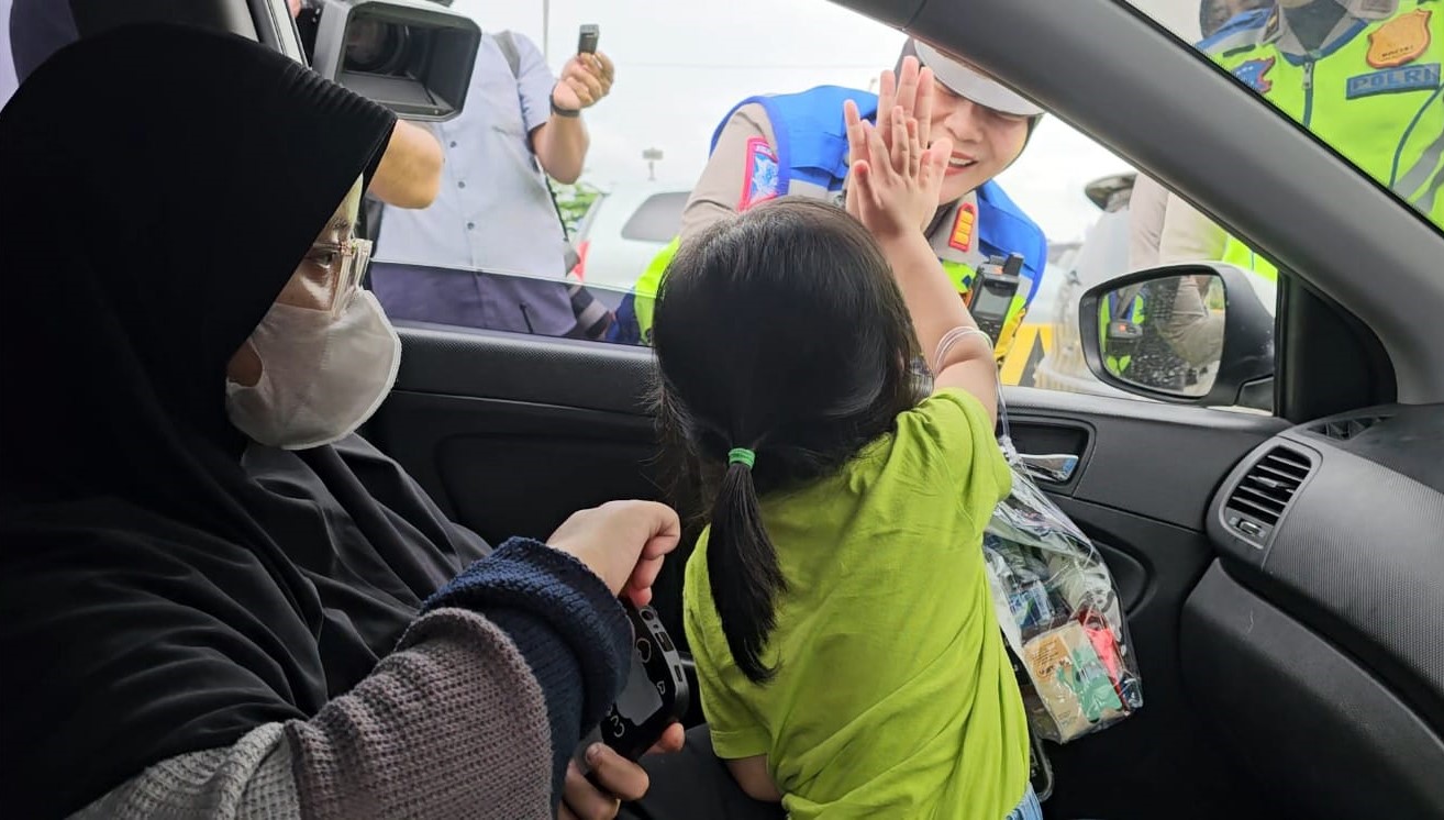 Seorang polwan menyapa pemudik yang antre menuju kapal feri di Pelabuhan Merak, Cilegon, Banten, Jumat (5/4).