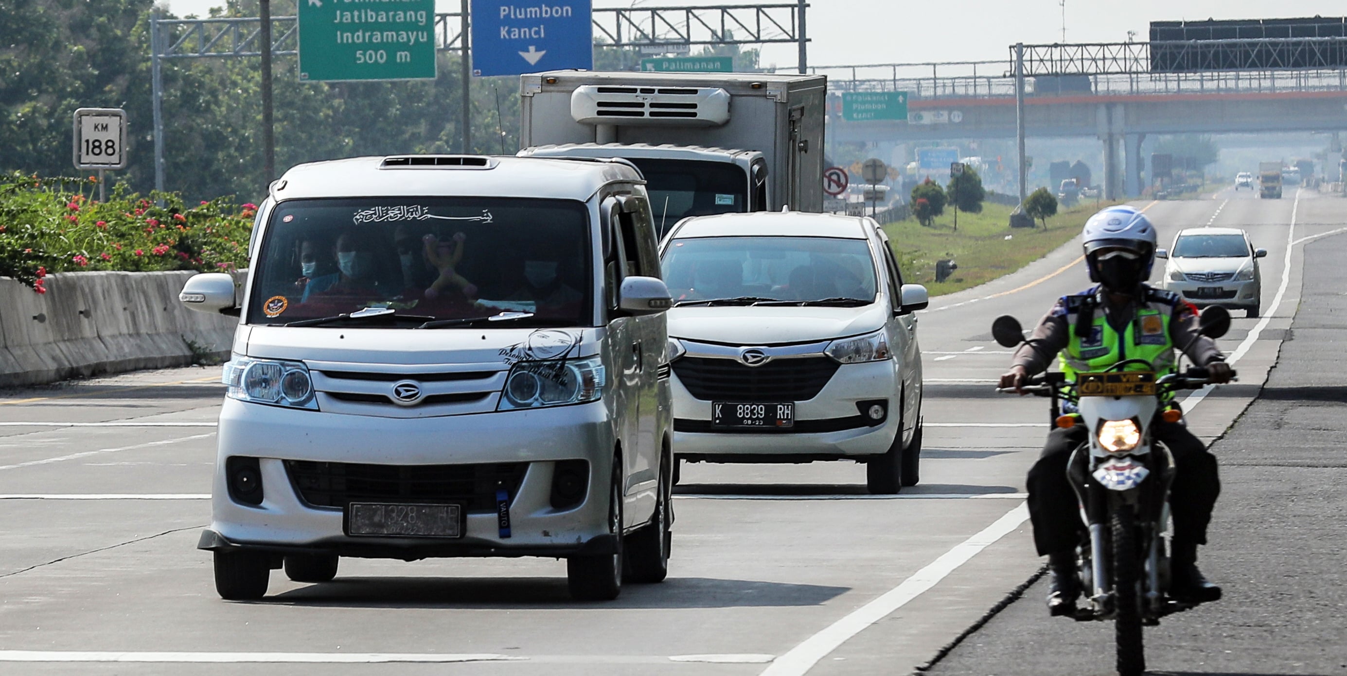 Polisi menggunakan sepeda motor mengawal travel gelap yang terjaring operasi penyekatan karena membawa pemudik
