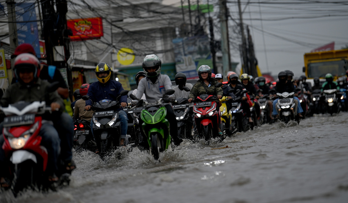 Pengendara motor melintasi banjir di kawasan perempatan Mampang, Pancoran Mas, Depok, Jawa Barat.