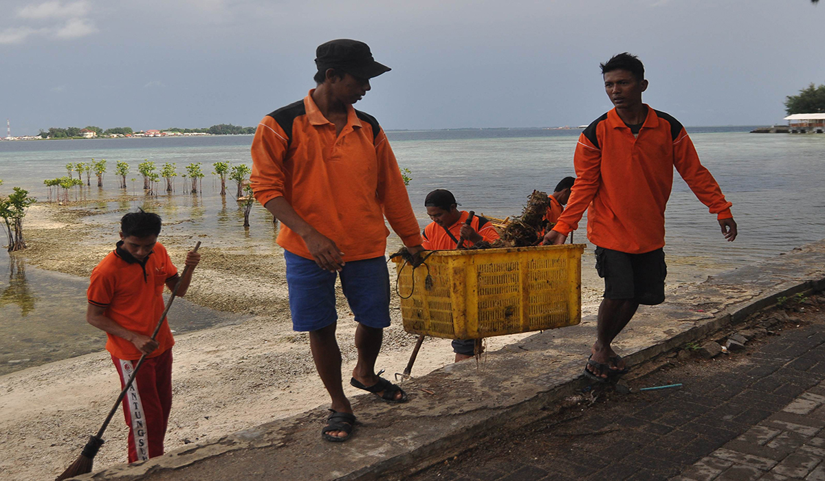 Sejumlah petugas kebersihan mengumpulkan sampah di sepanjang pantai di Pulau Pramuka, Kabupaten Administrasi Kepulauan Seribu, Jakarta.