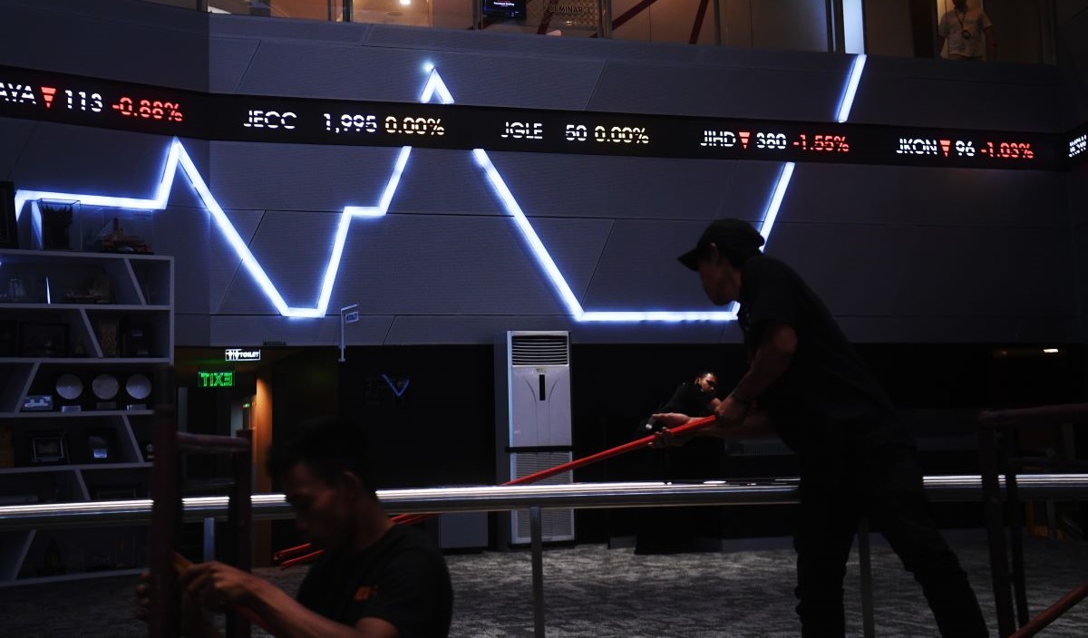 Pekerja melintasi layar digital pergerakan saham di Bursa Efek Indonesia, Jakarta, Rabu (13/3/2024).
