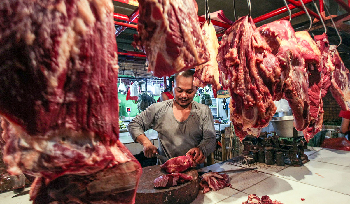 Pedagang memotong daging sapi untuk pembeli di Pasar Cibinong, Kabupaten Bogor, Jawa Barat, Senin (1/4).