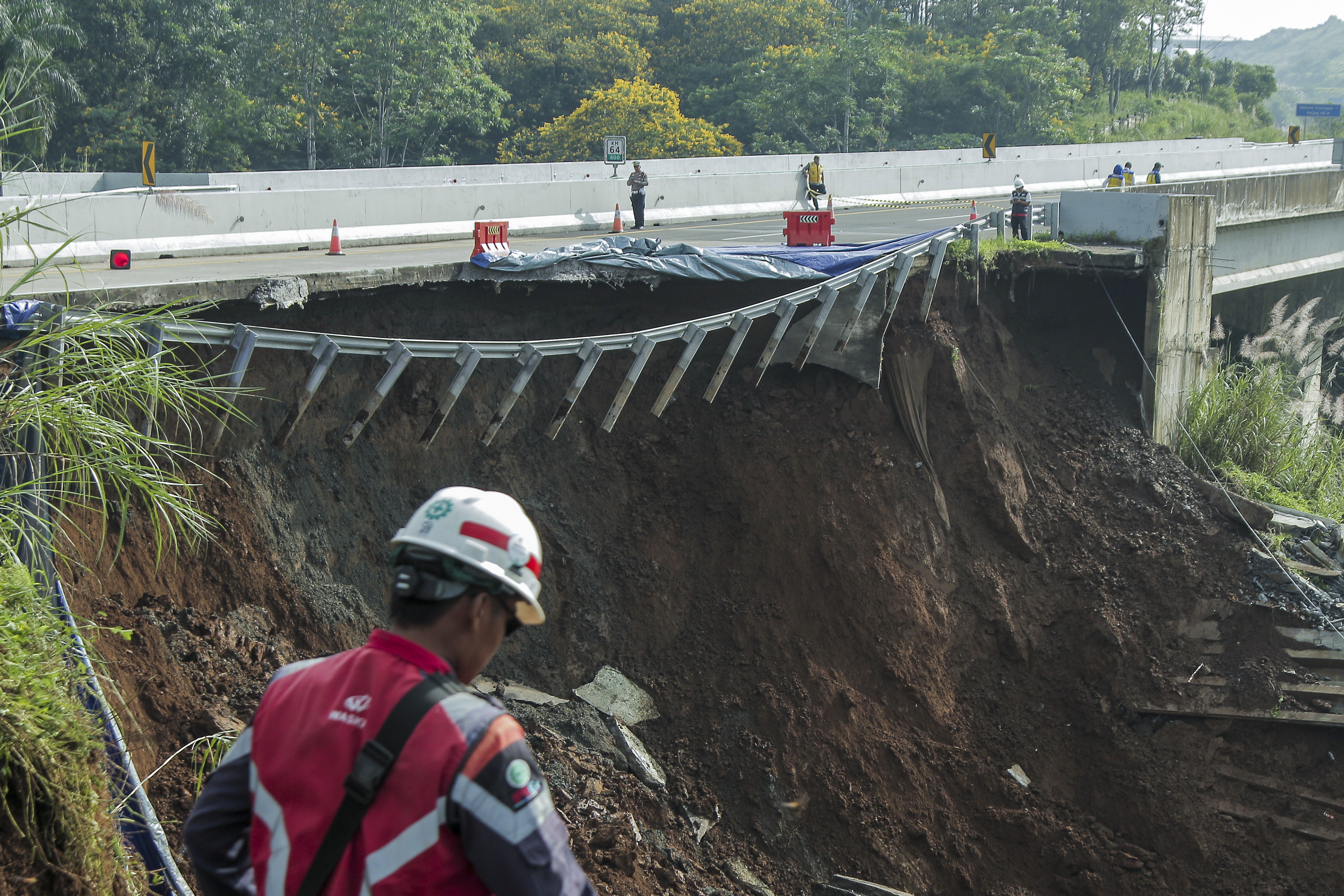 Petugas melintas di sekitar jalan tol yang amblas di ruas tol Bocimi KM 64, Sukabumi, Jawa Barat