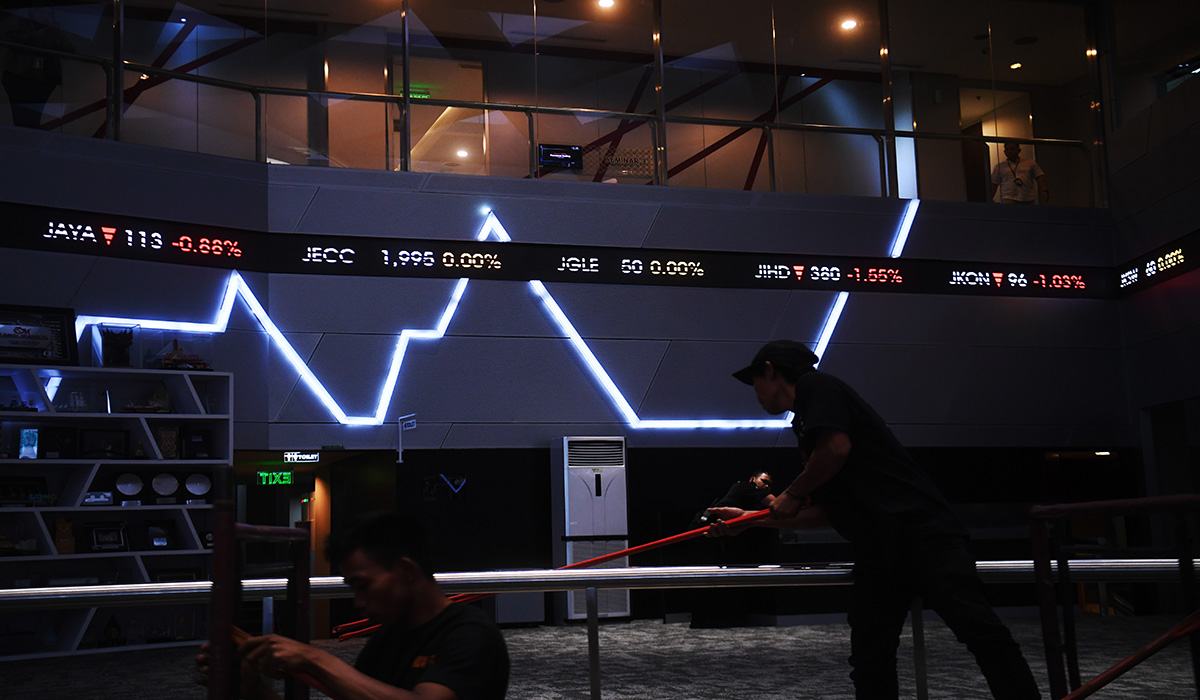 Pekerja melintasi layar digital pergerakan saham di Bursa Efek Indonesia, Jakarta, Rabu (13/3).