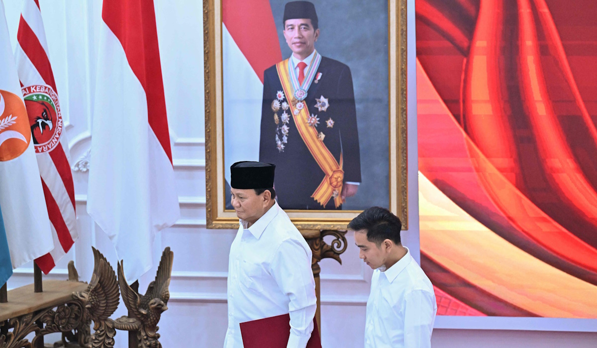Presiden terpilih Prabowo Subianto dan wakil presiden terpilih Gibran Rakabuming Raka berjalan melewati foto Presiden Joko Widodo 
