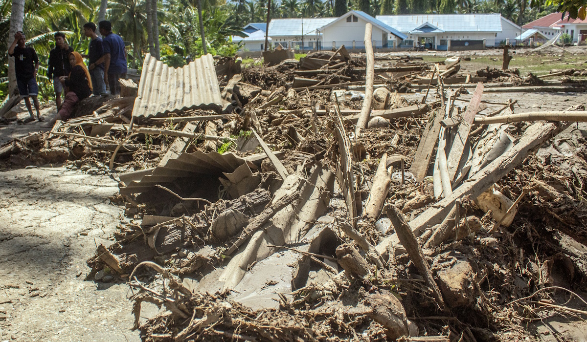 Sejumlah warga berdiri di dekat tumpukan material kayu dan lumpur pascabanjir bandang di Desa Balongga, Sigi, Sulawesi Tengah, 