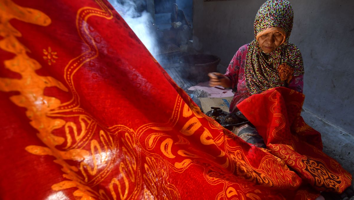Seorang warga sedang menenun batik.