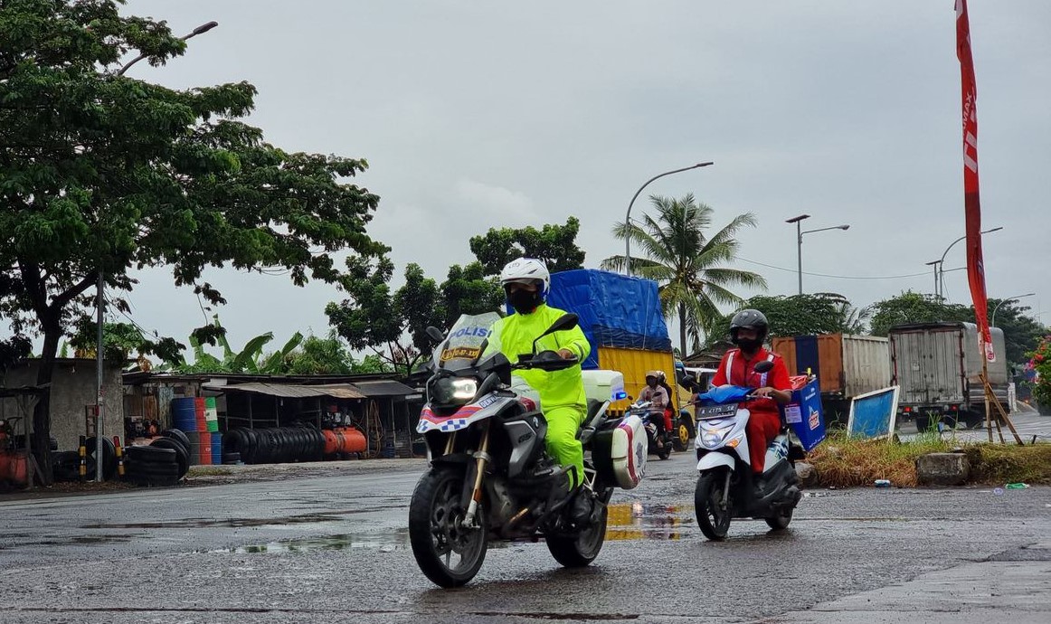 Pengendara motoris dikawal petugas bergerak dari rest area menuju kendaraan pemudik yang kehabisan bensin di tol. 