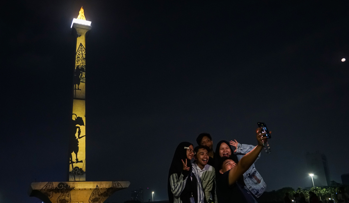 Pengunjung berswafoto saat pertunjukan video mapping Monas di Monumen Nasional, Jakarta.