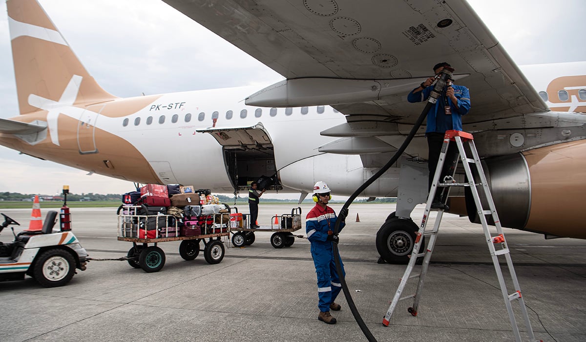 Petugas mengisi bahan bakar avtur ke pesawat.