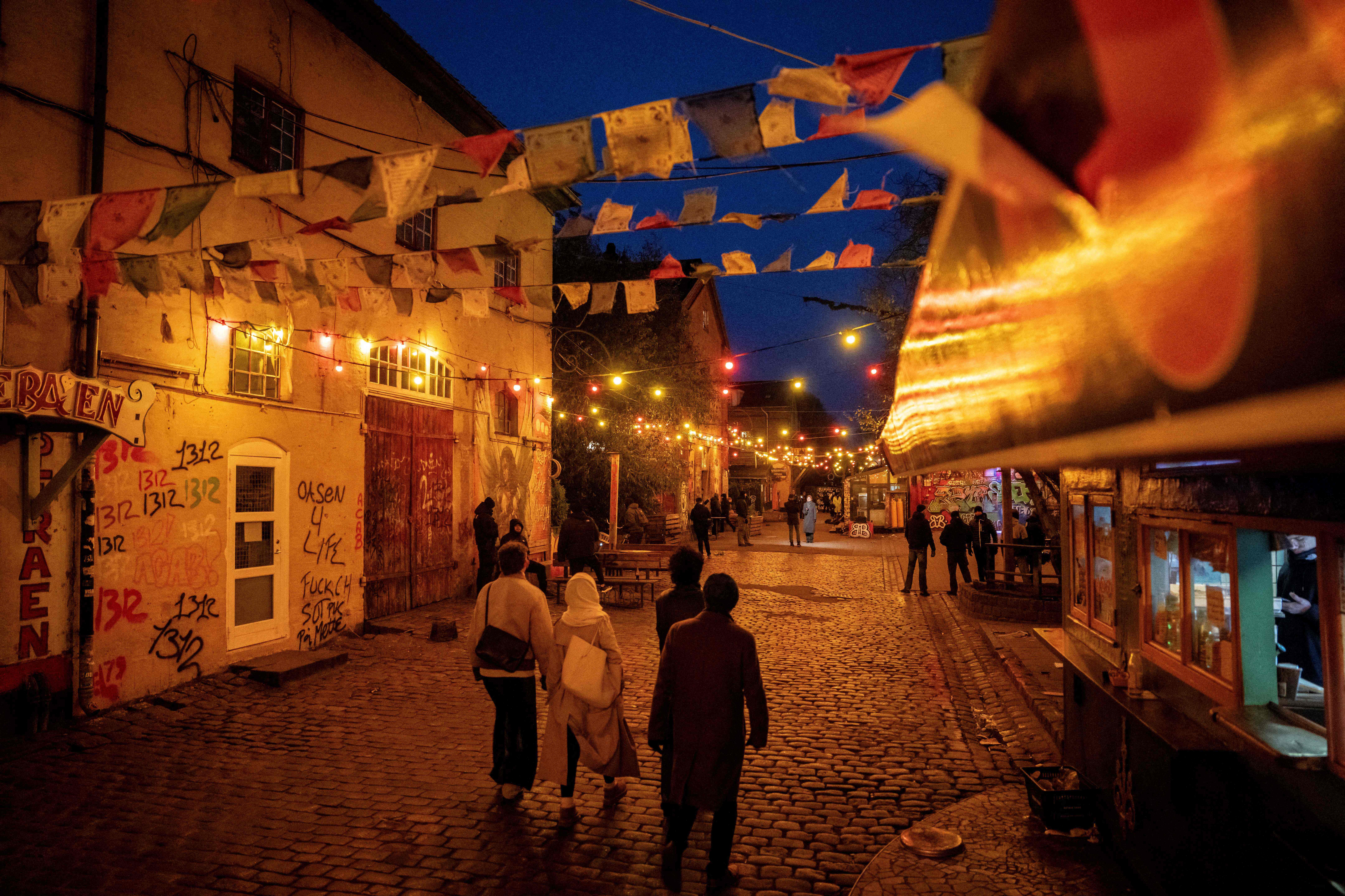 Pejalan kaki berjalan di sepanjang kios di Pusher Street di Christiania, Kopenhagen, Denmark pada 22 November 2023.