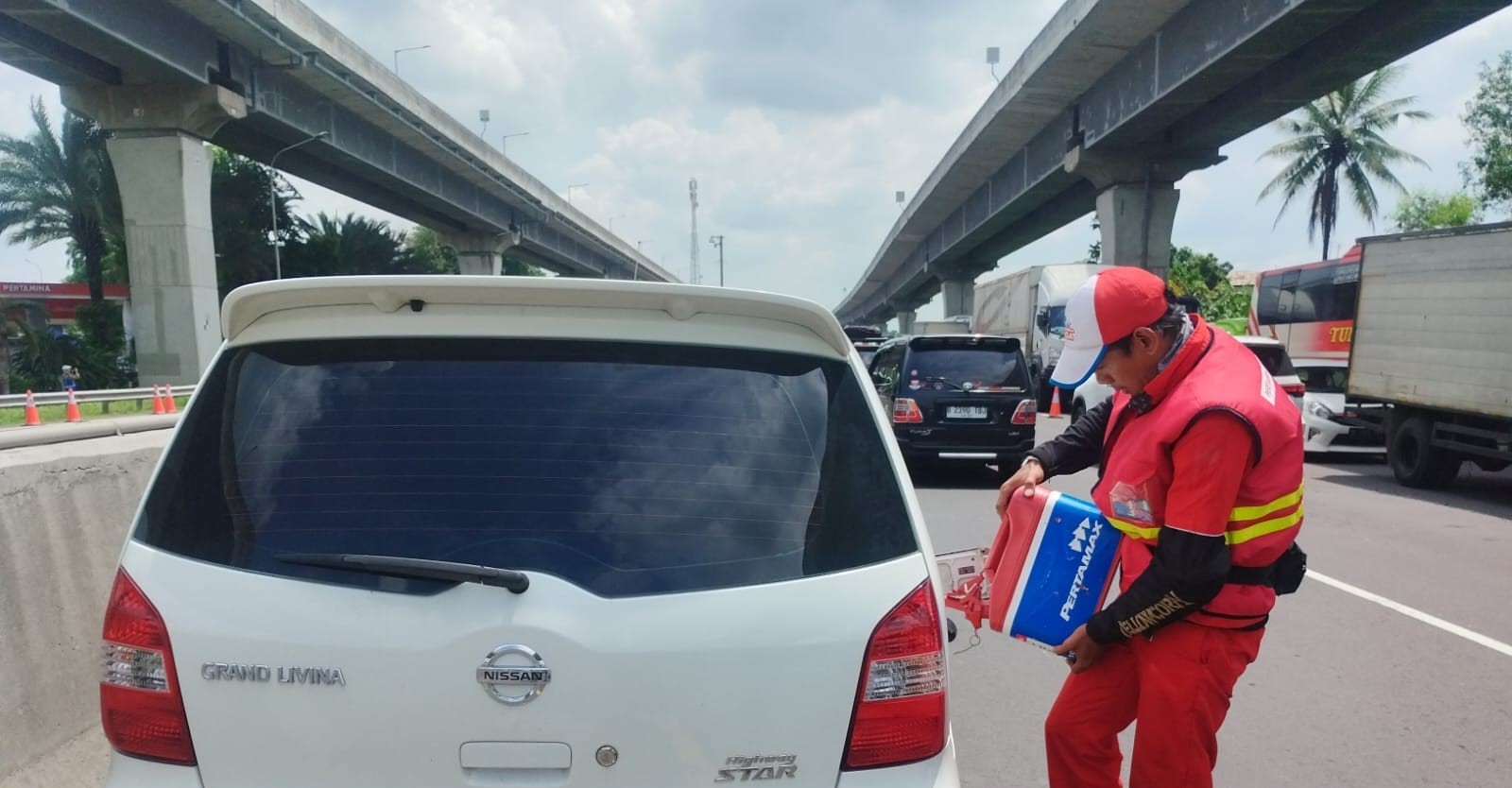 Motoris mengisi bensin ke sebuah mobil yang kehabisan bahan bakar imbas macet di Tol Jakarta-Cikampek, Senin (15/4).