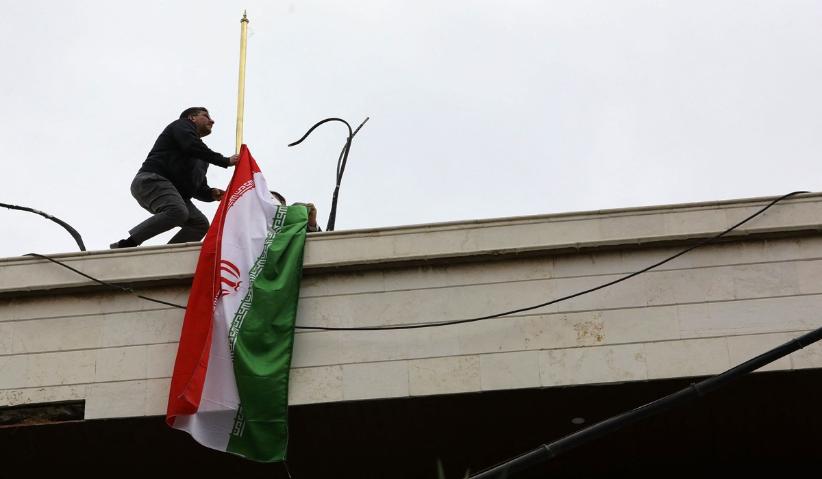 Seorang staf memasang bendera Iran di gedung konsuler Iran yang baru di Damaskus, Suriah.