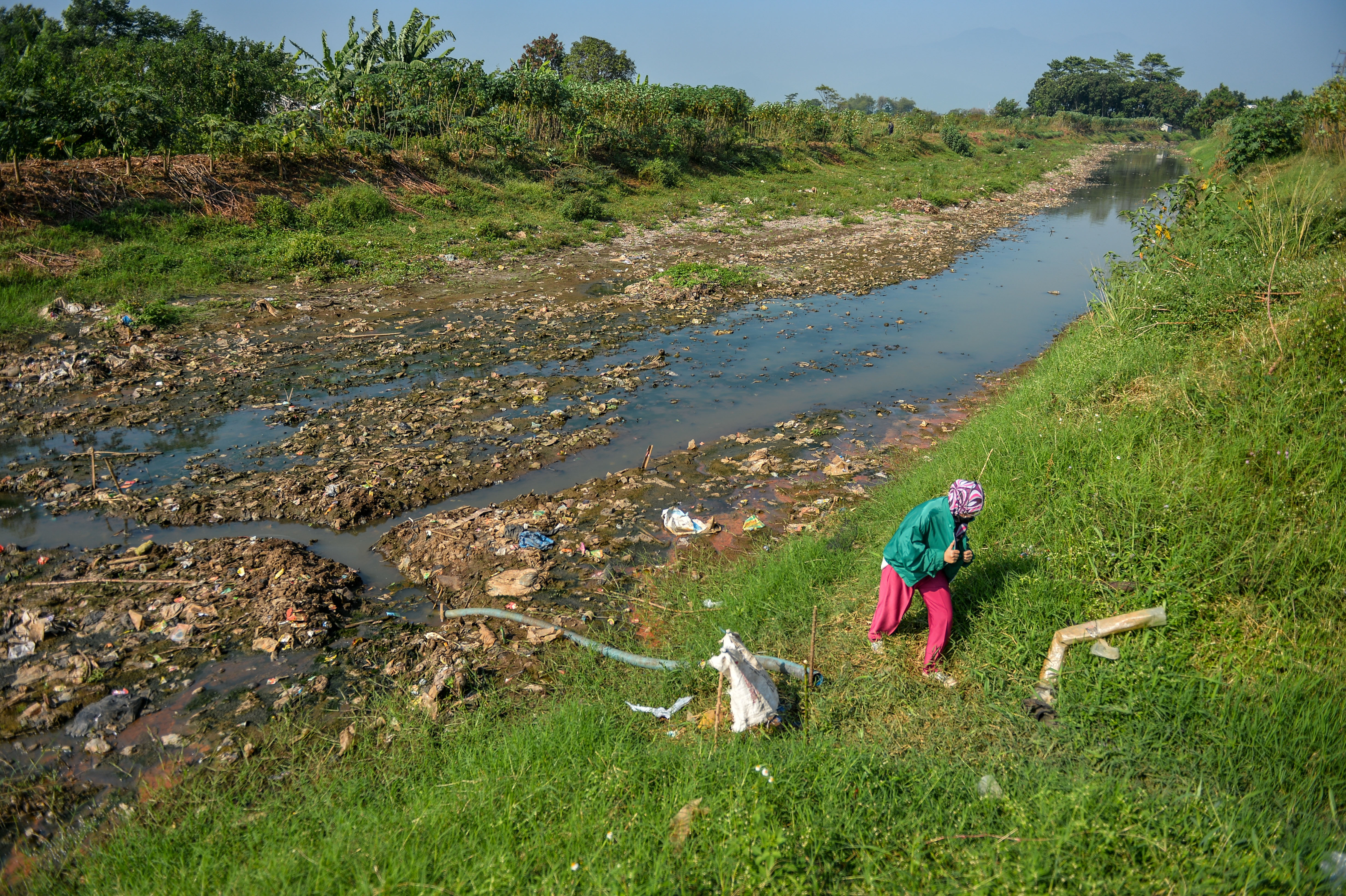 Warga berjalan di bantaran Sungai Cikeruh yang mengering di Tegalluar, Kabupaten Bandung, saat musim kemarau. 