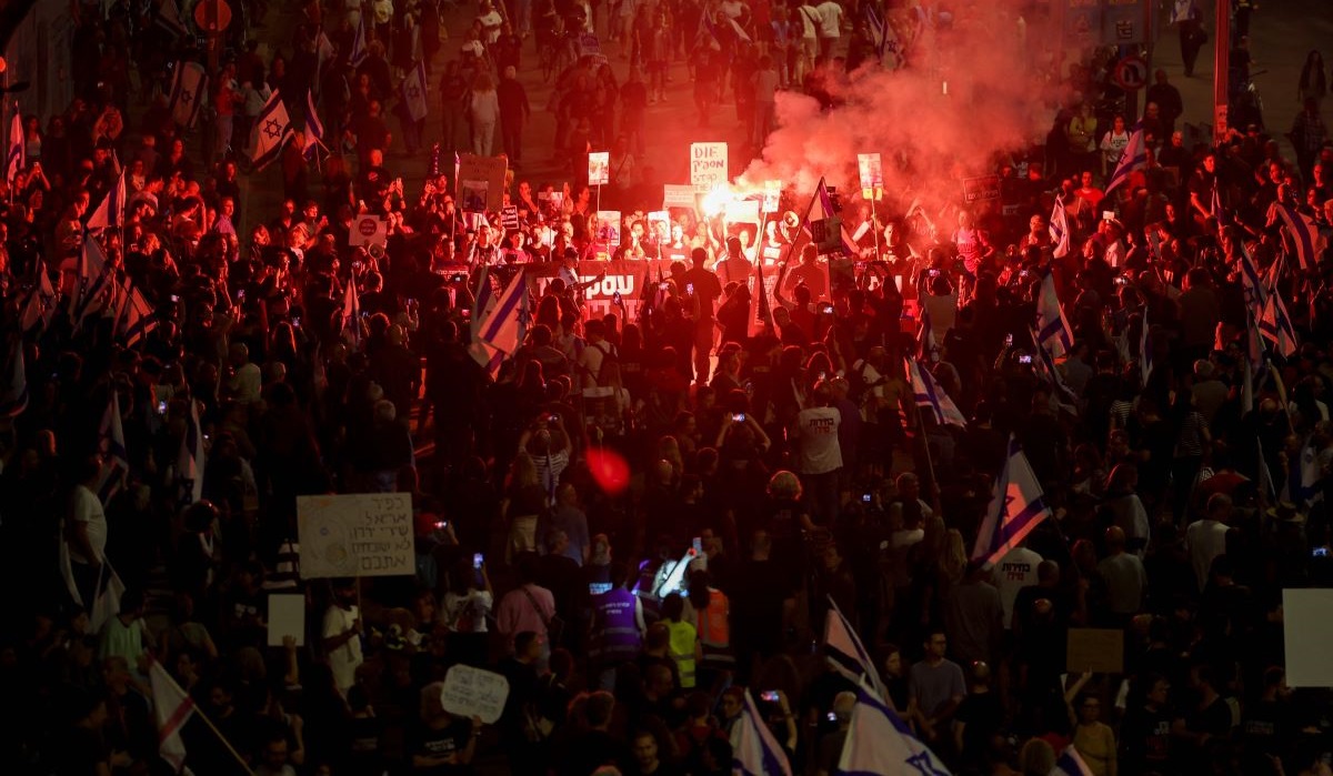 Kerabat sandera yang ditawan oleh militan Palestina dan pendukung mereka menyalakan suar dalam unjuk rasa di Tel Aviv, Israel.