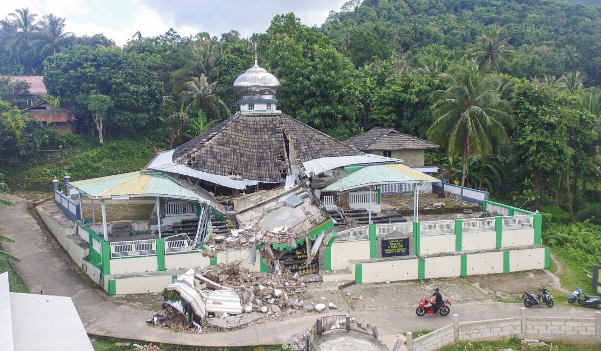 Ilustrasi: warga melintas di dekat Masjid Jamik Al Muhajirin yang sebangian bangunannya roboh akibat gempa di Pulau Bawean 