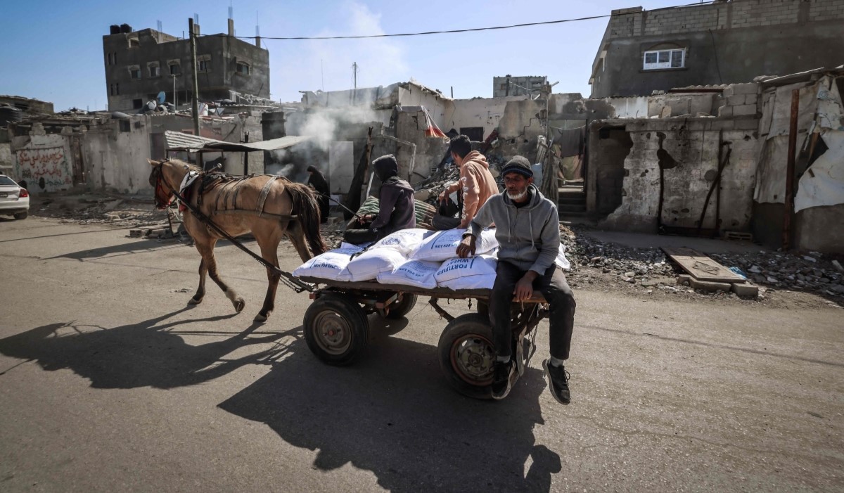 Ilustrasi: warga Palestina mengangkut karung tepung yang didistribusikan oleh PBB di kamp pengungsi Rafah di Jalur Gaza selatan 