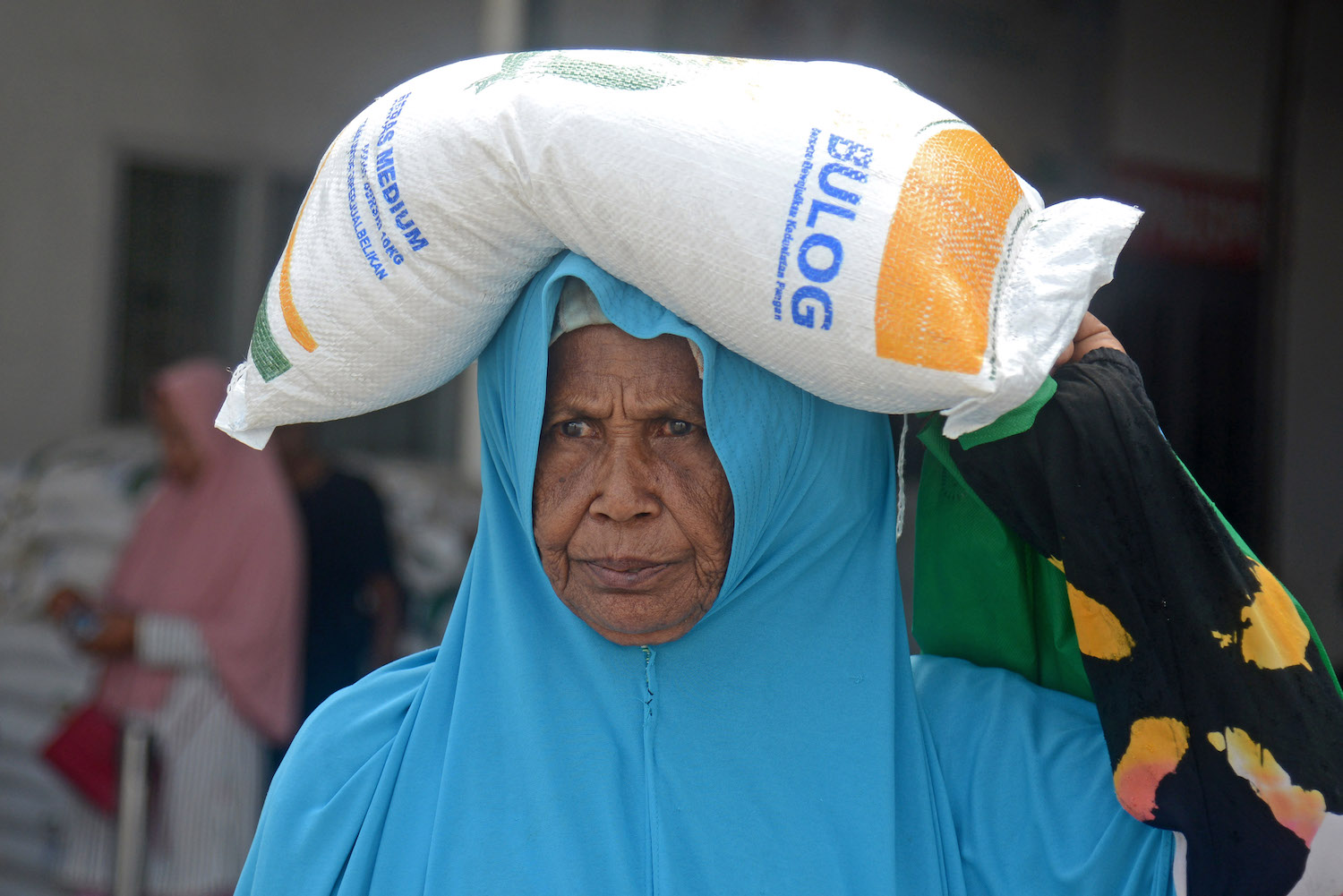 Keluarga penerima manfaat (KPM) membawa bantuan sosial pangan beras.