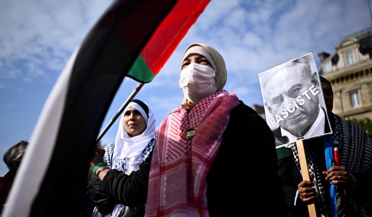 Seorang pengunjuk rasa memegang poster Perdana Menteri Israel Benjamin Netanyahu dan bertuliskan Fasis di Paris, Prancis.