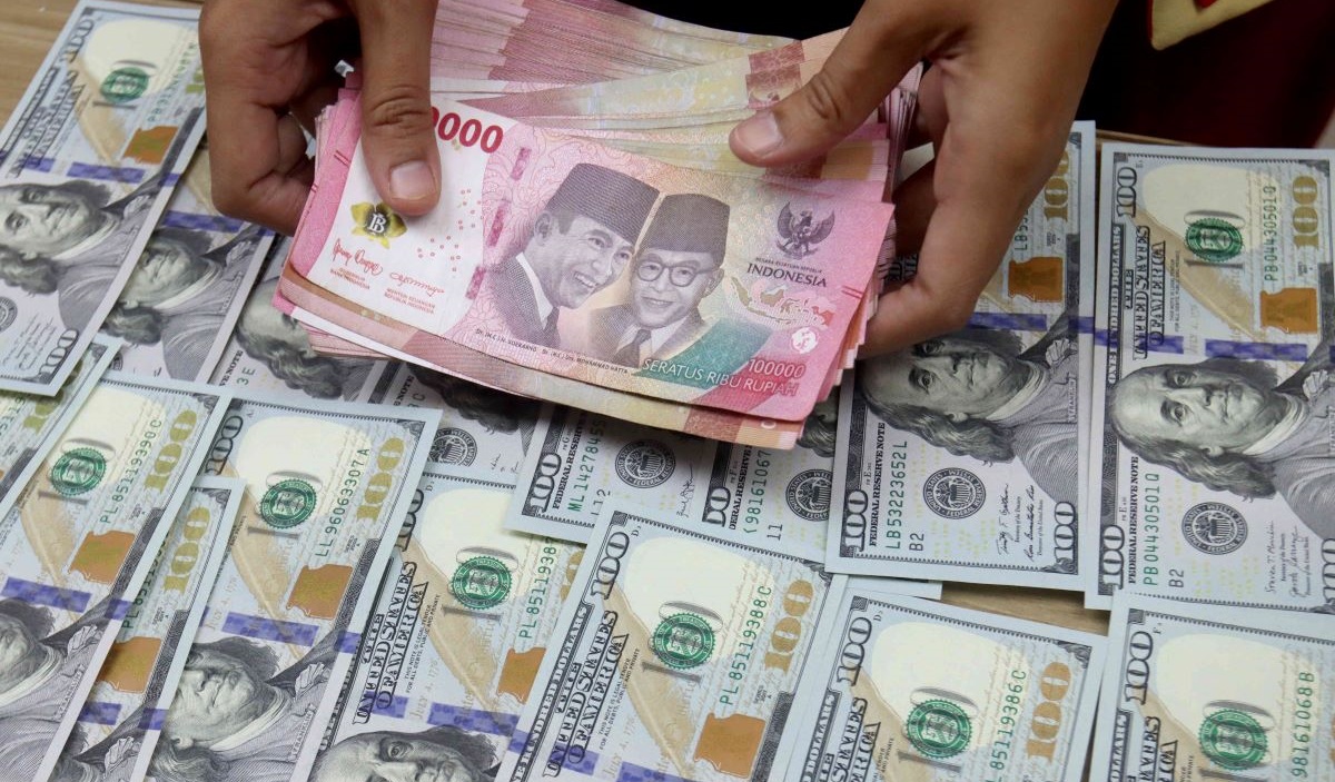 Petugas teller menunjukan uang rupiah dan dolar AS yang akan ditransaksikan, di Jakarta, Kamis (15/2/2024).