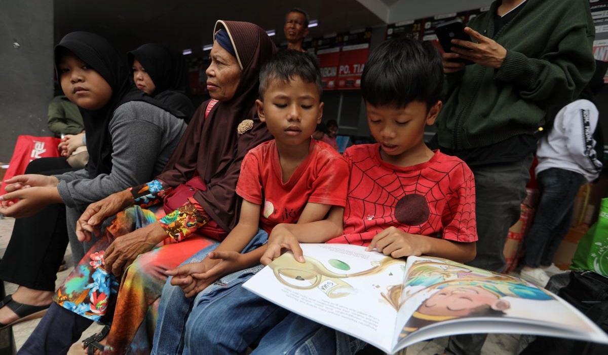 Anak membaca buku yang diberikan petugas dari Badan Pengembangan dan Pembinaan Bahasa (Badan Bahasa).