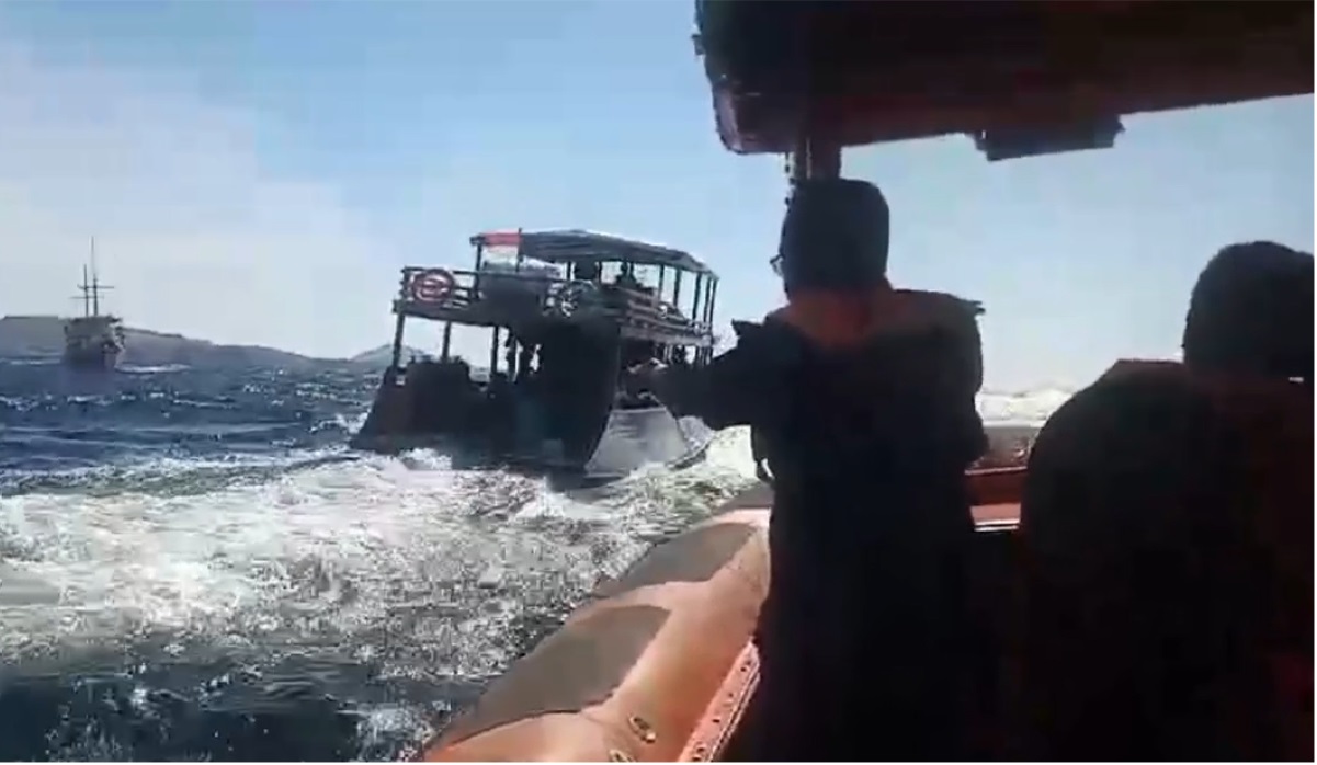 Petugas mendekati kapal wisata yang terbakar.