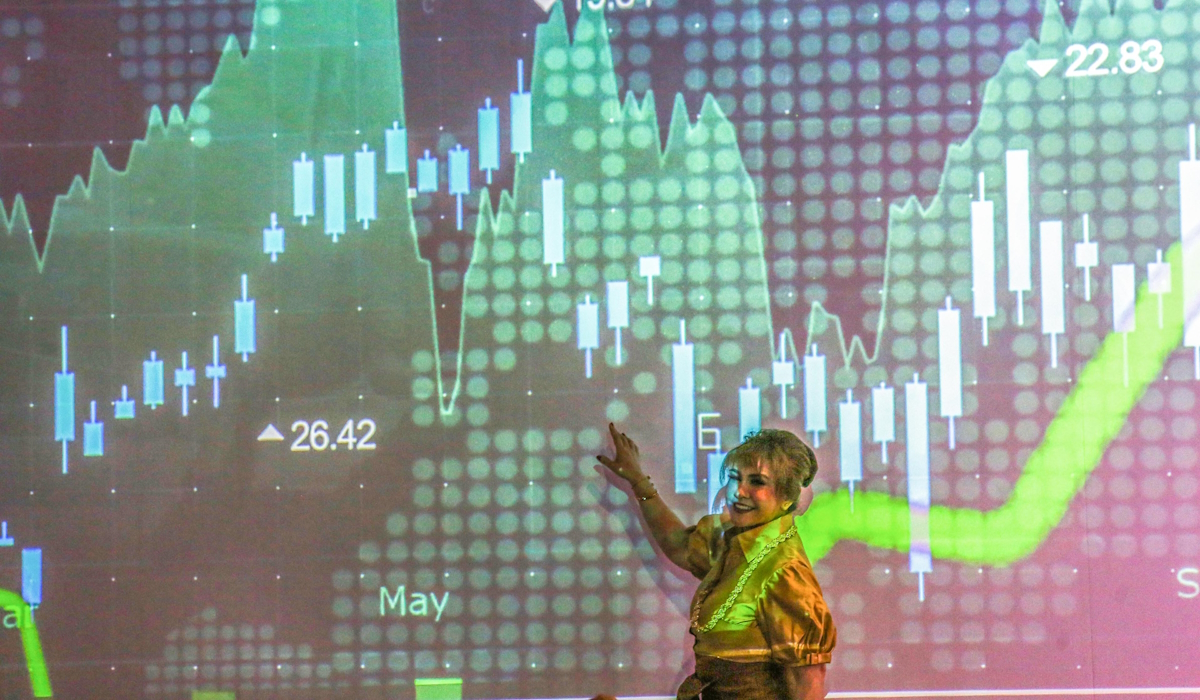 Pengunjung berfoto dengan latar belakang layar yang menampilkan pergerakan Indeks Harga Saham Gabungan (IHSG) di Bursa Efek Indonesia