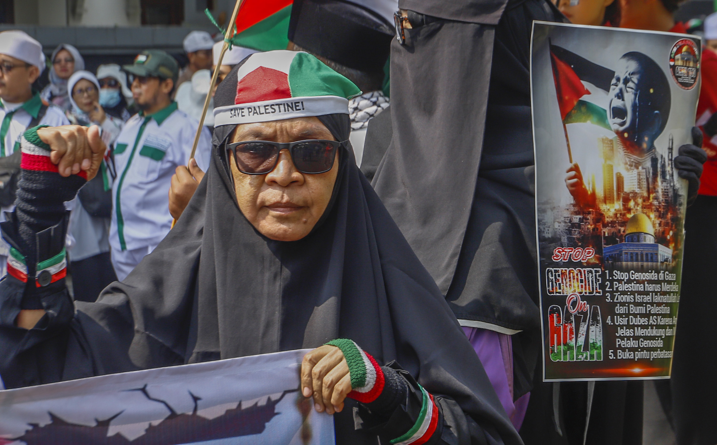 Pengunjuk rasa memegang poster Stop Genosida di Gaza saat Aksi Bela Palestina di Kantor Kedutaan Besar Mesir, Jakarta, Minggu (19/5/2024)