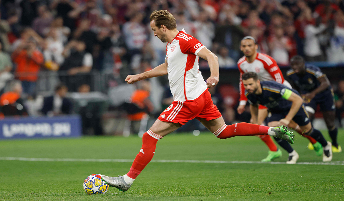 Striker Bayern Muenchen Harry Kane tengah menendang bola saat menjadi eksekutor penalti saat timnya melawan Real Madrid.