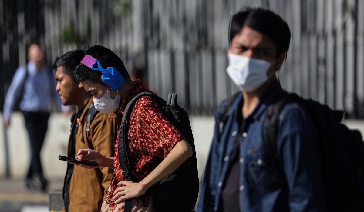 Pekerja tersinari cahaya matahari saat akan menyeberang di kawasan Sudirman, Jakarta.