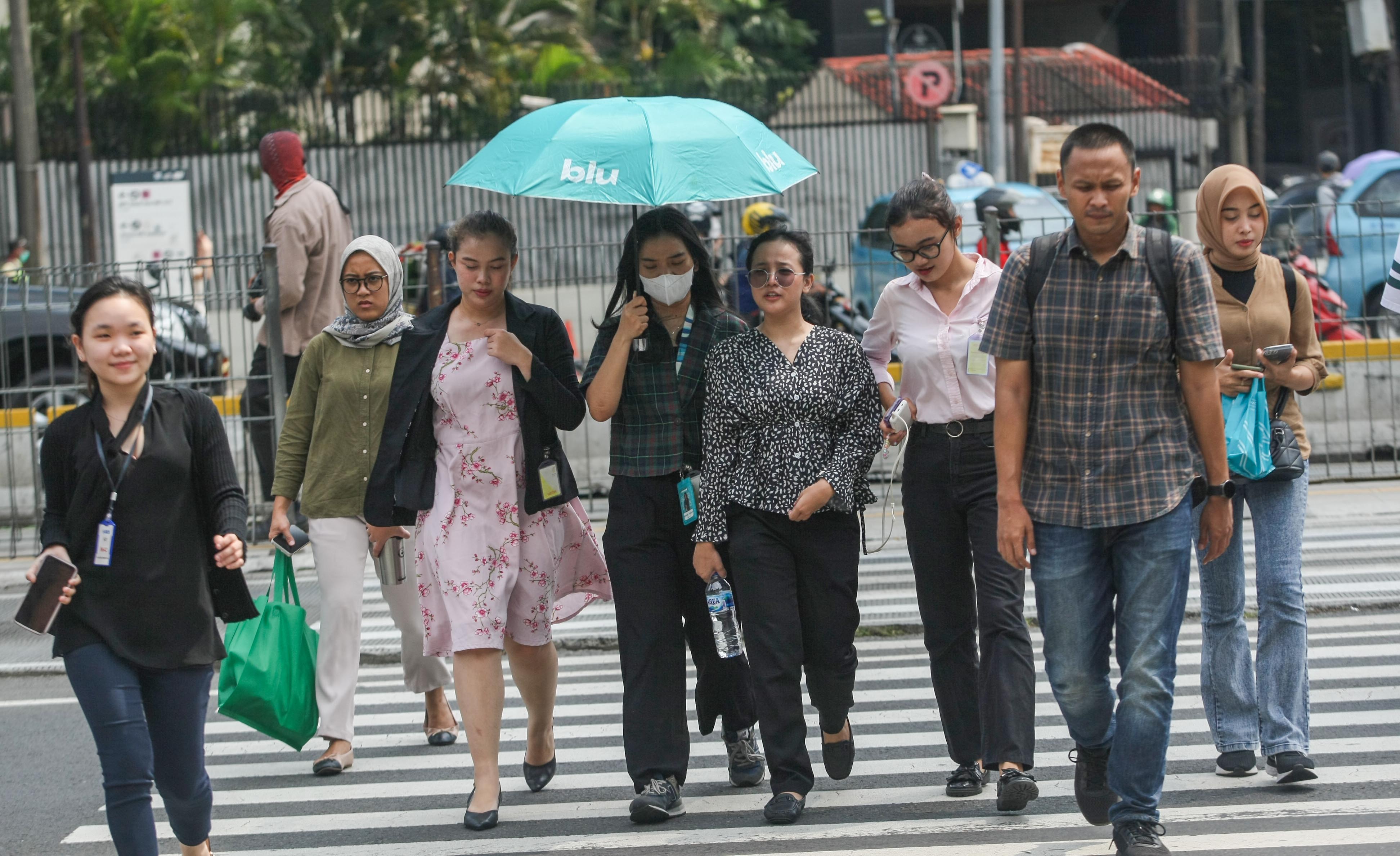 Para pejalan kaki membawa payung untuk melindungi dari dari suhu panas matahari di kawasan Tosari, Jakarta