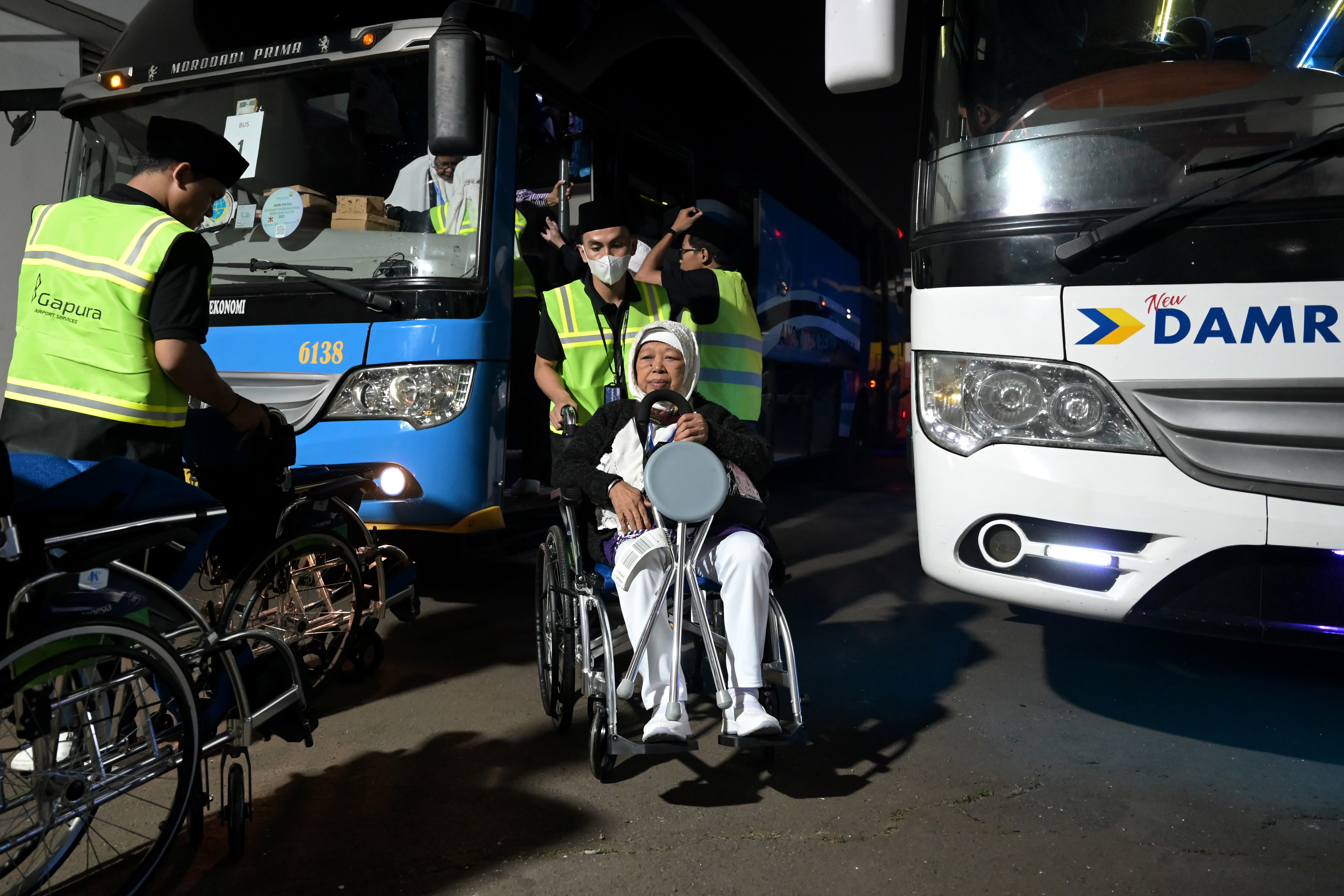 Calon haji dibantu petugas menggunakan kursi roda sebelum diberangkatkan ke Tanah Suci di Bandara Soekarno Hatta, Tangerang, Banten. 